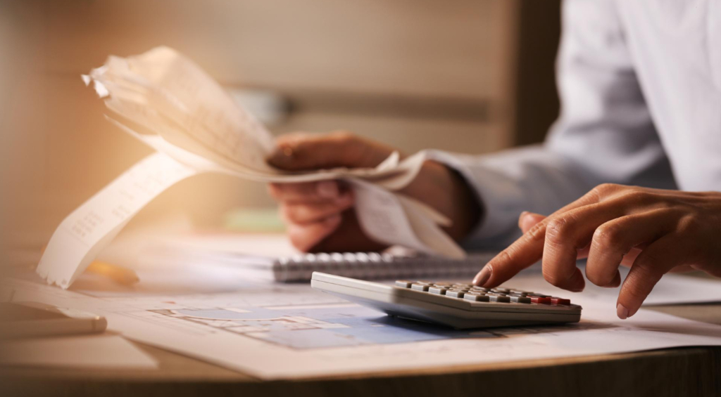 closeup economist using calculator while going through bills taxes office